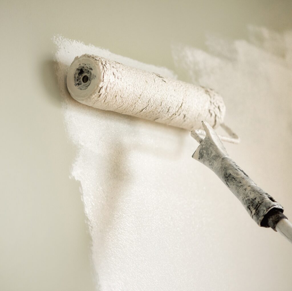 Hand painting wall with paint roller, pastel color. Appartment renovation, repair, building and home